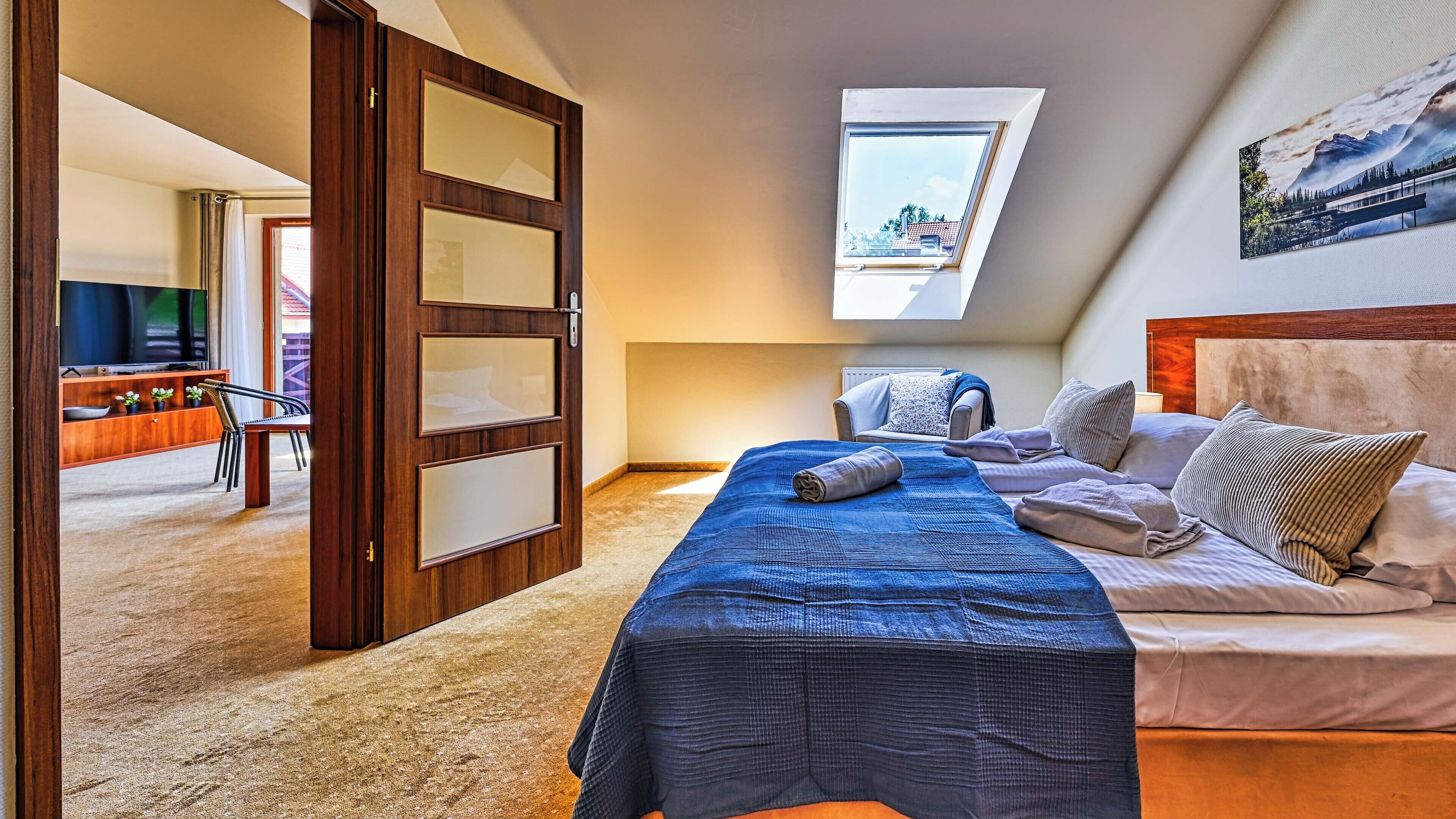 Un dormitorio con cama, vista de una montaña a través de un tragaluz y una puerta de madera con paneles de vidrio esmerilado.