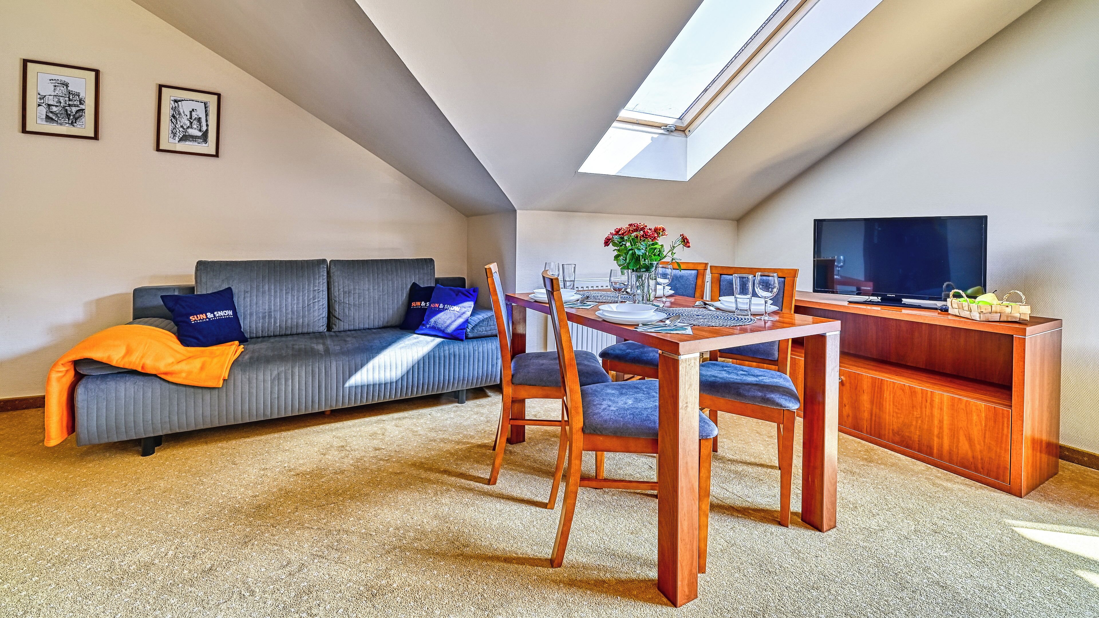 A modern loft apartment with a dining area, a sofa, and a TV.