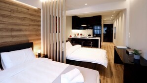 A modern hotel room with two beds, a wooden accent wall, a desk with a chair, and a small potted plant. - Segundo Molo Suites (Thessaloniki)