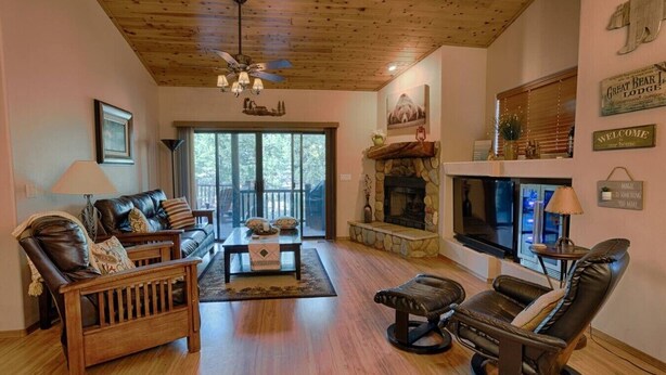 A cozy living room with leather furniture, a fireplace, and a large window.