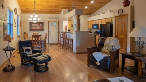 A spacious living area with a wooden ceiling, a kitchen with wooden cabinets, and a dining area with a table and chairs.