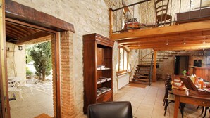 A rustic interior with a wooden bookshelf, a dining area with a table and chairs, and a staircase leading to an upper level. - Mas DISTAISE, 5 bedrooms, 4 bathrooms, pool, billiards.  Vacations with family and friends (Grane)