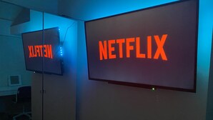 Deux grands écrans affichant le logo de Netflix, ce qui indique qu’il s’agit d’une pièce équipée d’appareils compatibles avec Netflix.