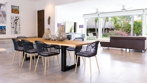 A modern dining area with a wooden table and black chairs, a sofa, and artwork on the walls.