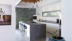 A modern kitchen with a large island, bar stools, and a stone backsplash.