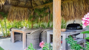 An outdoor dining area with wicker furniture and a grill.