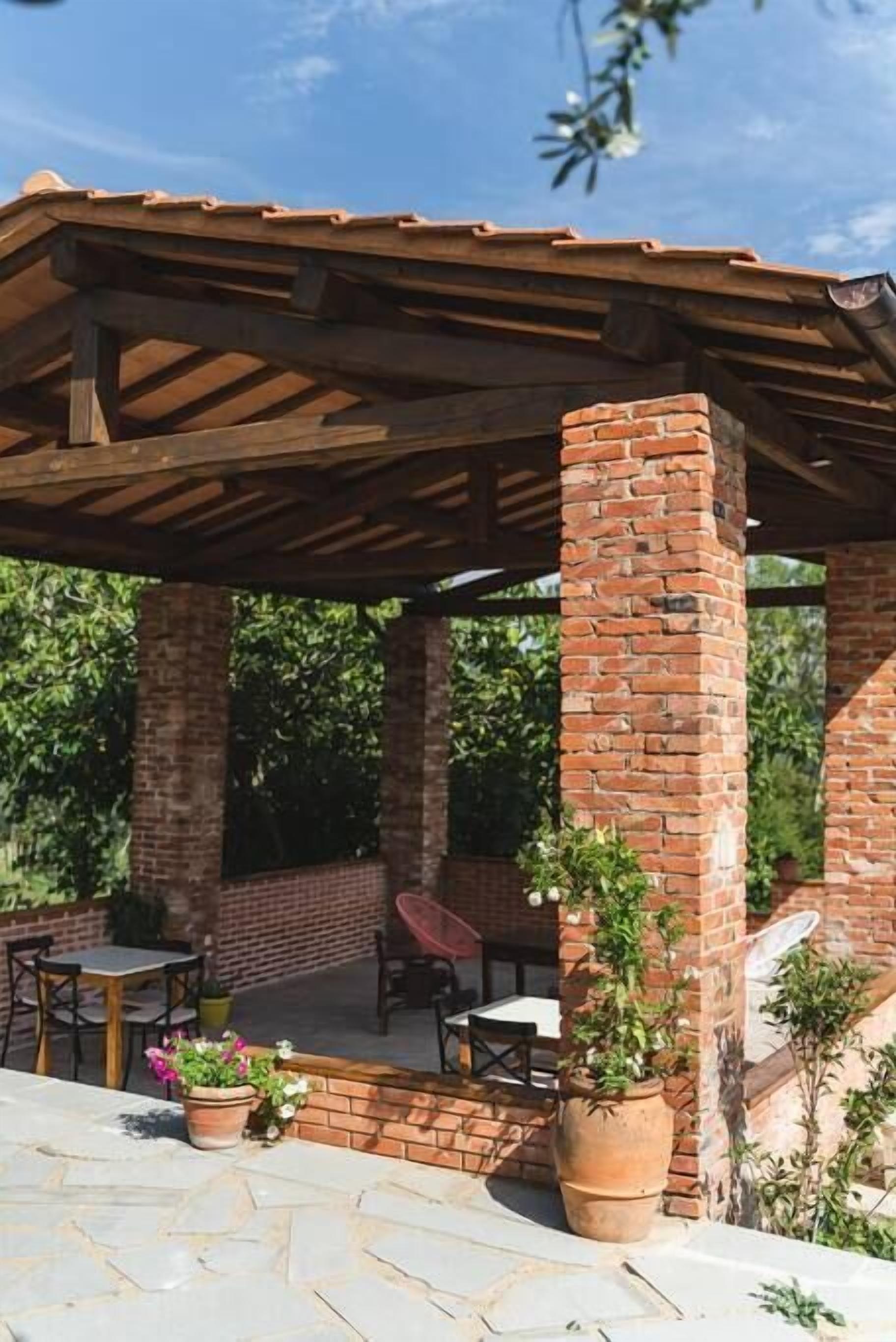 Un'area patio coperta con pilastri in mattoni, mobili da esterno e piante in vaso.