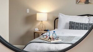 A neatly made bed with white linens, a bedside table with a lamp, and a tray with toiletries. - Dublin 2BR | Pet friendly | 0 stairs | King bed (Dublin)