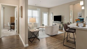 A modern living room with a sofa, a coffee table, a TV, and a kitchen area with a bar. - Dublin 2BR | Pet friendly | 0 stairs | King bed (Dublin)