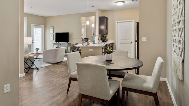 A modern kitchen with a central island, a dining area with a round table and chairs, and a living space with a TV and seating area. - Dublin 2BR | Pet friendly | 0 stairs | King bed (Dublin)