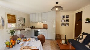 Un ambiente compatto con angolo cottura, zona pranzo e divano.