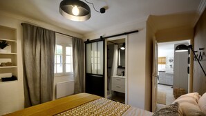 Una camera da letto con un letto, un comodino, un armadio e un bagno visibile attraverso una porta aperta.