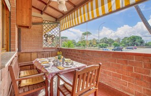A dining area with a table set for four, a wooden bench, and a view of a parking lot and greenery outside. - 2 bedroom lovely apartment in Grosseto (Grosseto)