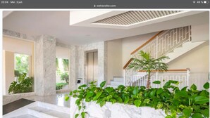 Eine großzügige Lobby mit Marmorböden, einer Treppe und üppiger, grüner Bepflanzung.