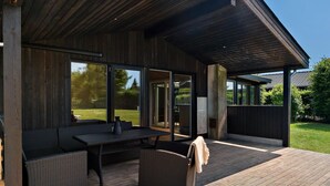Une terrasse extérieure aménagée avec des meubles en osier, une table et un banc.