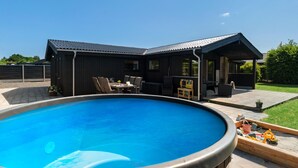 Une maison moderne dotée d’une piscine, d’un espace salon extérieur et d’un patio couvert.
