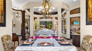Un coin repas agrémenté d’un lustre, d’une table dressée pour quatre personnes et offrant une vue sur l’extérieur grâce à de grandes fenêtres.