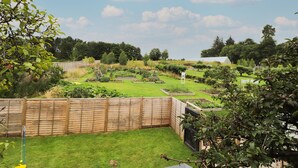Un giardino curato con aiuole rialzate, una recinzione in legno e diverse piante.