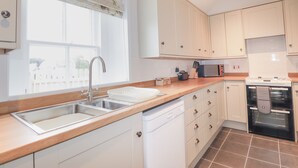 Una cucina moderna con mobili bianchi, un lavello in acciaio inossidabile, una lavastoviglie, un forno a microonde e un forno.