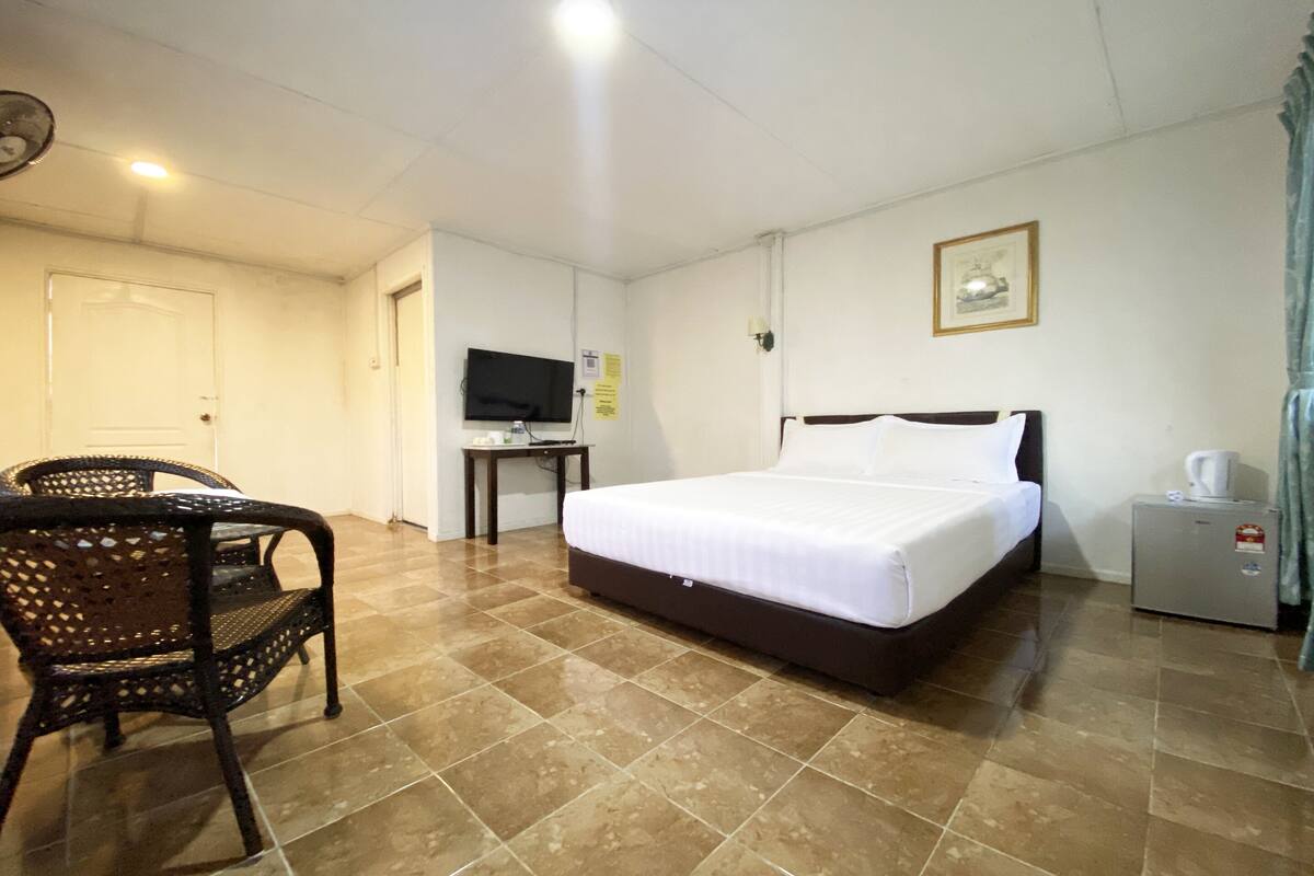 A hotel room with a bed, a television, a small table, and a chair.