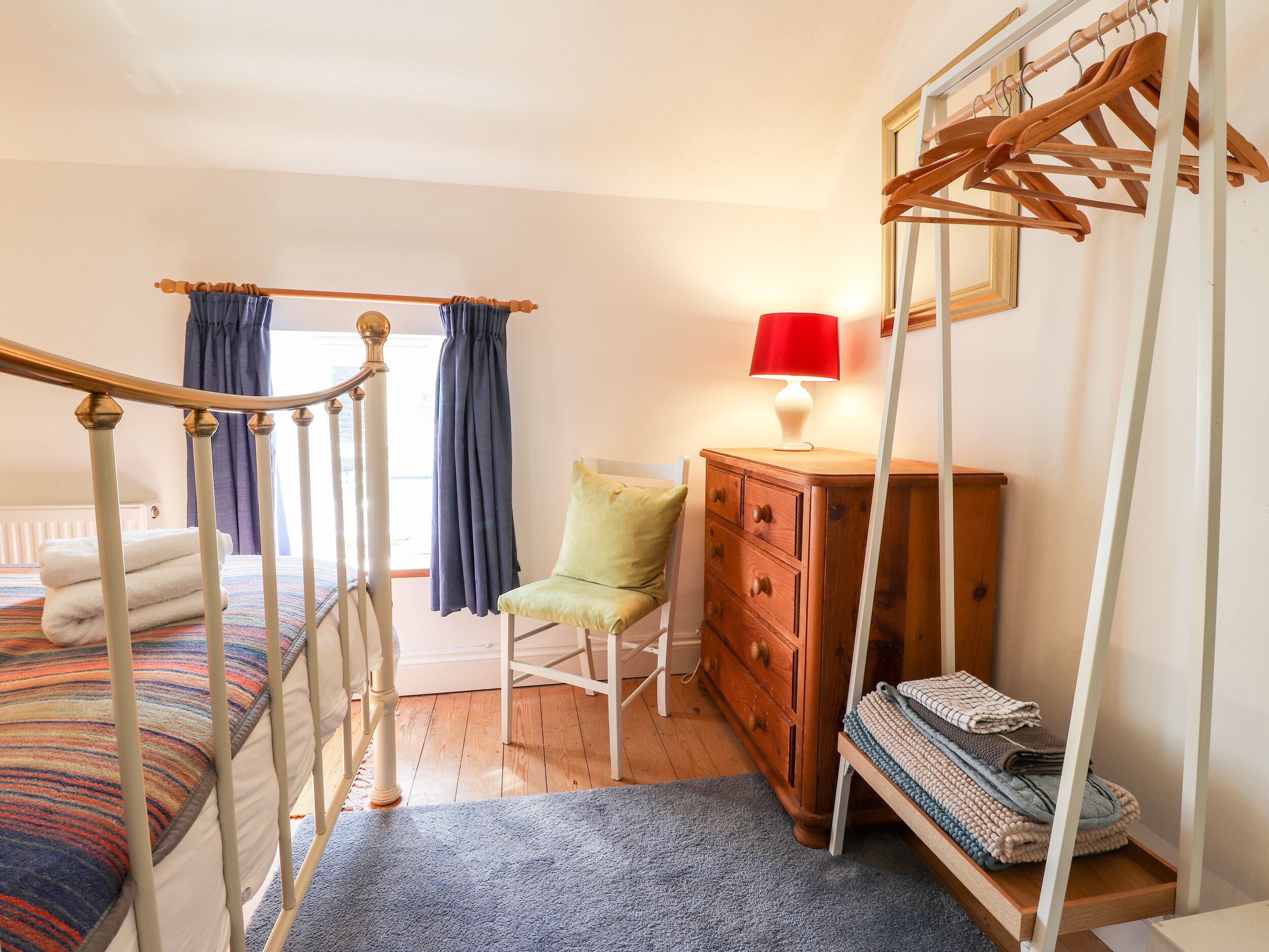 A bedroom with a four-poster bed, a wooden dresser, a chair, and a lamp.