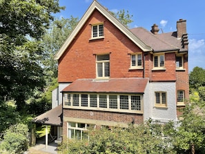 A two-story house with a steeply pitched roof, multiple windows, and a brick exterior.