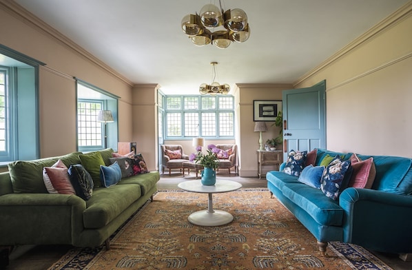 A living room with two sofas, a coffee table, and a chandelier.