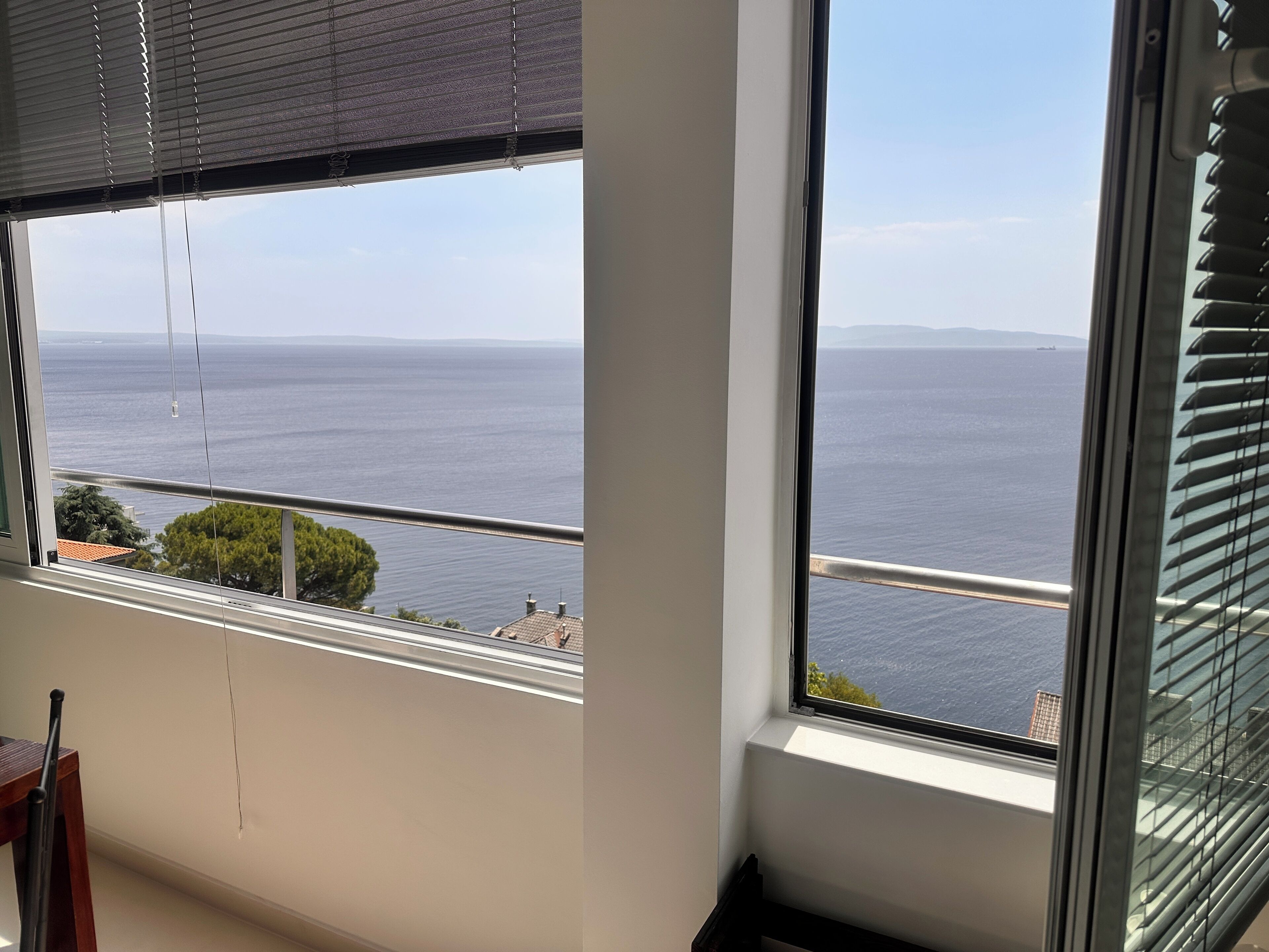 A room with a large window overlooking a body of water and distant land.