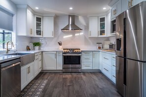 A modern kitchen with stainless steel appliances, white cabinetry, and a patterned rug.