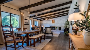 A spacious living area with a wooden dining table, chairs, and a fireplace. - Spa + Fire Pit + Court | Paso Robles Wine Country | Na Hoku Ranch (Atascadero)