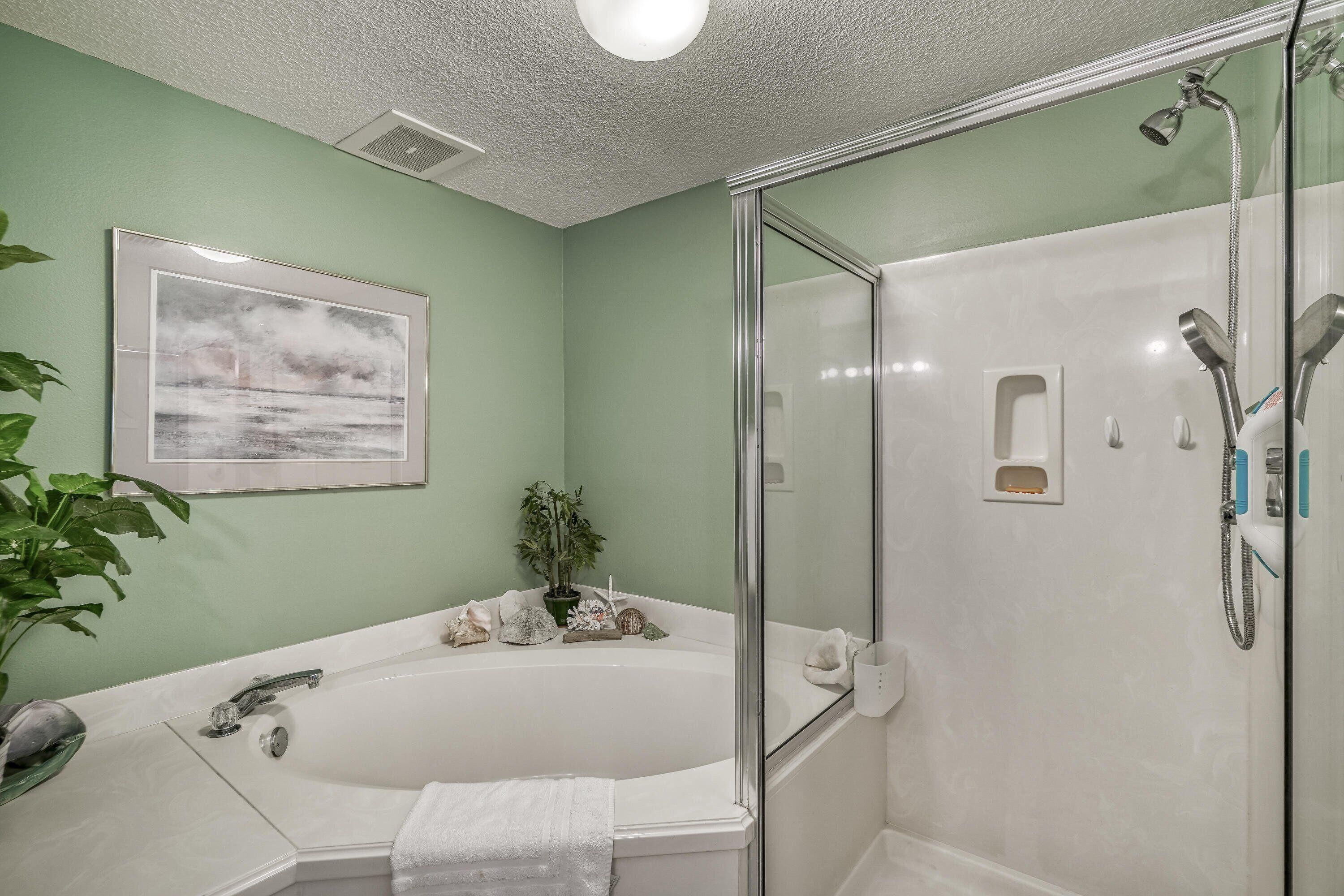 A bathroom with a bathtub, a glass-enclosed shower, a sink, and a framed picture on the wall.