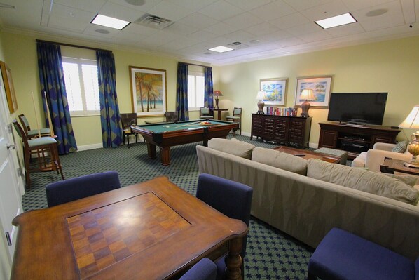 A room with a pool table, a sofa set, a television, and a bookshelf. - Updated Modern Poolside Condo! (Bonita Springs)