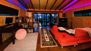 A modern living room with a red sofa, a bookshelf, and a large window. - Unique funky Arthouse ‘Franks Place’ Hunchy Valley (Hunchy)