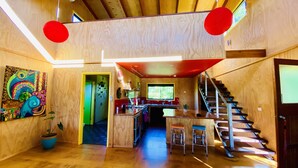 A modern kitchen with wooden cabinetry, a central island, and a staircase leading to an upper level. - Unique funky Arthouse ‘Franks Place’ Hunchy Valley (Hunchy)