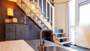 Une cuisine avec un plan de travail en bois, un évier en acier inoxydable, une bouteille et un luminaire suspendu.