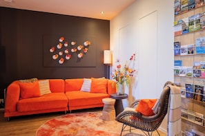 A modern living room with a sofa, a round rug, a chair, a vase with flowers, and a bookshelf.