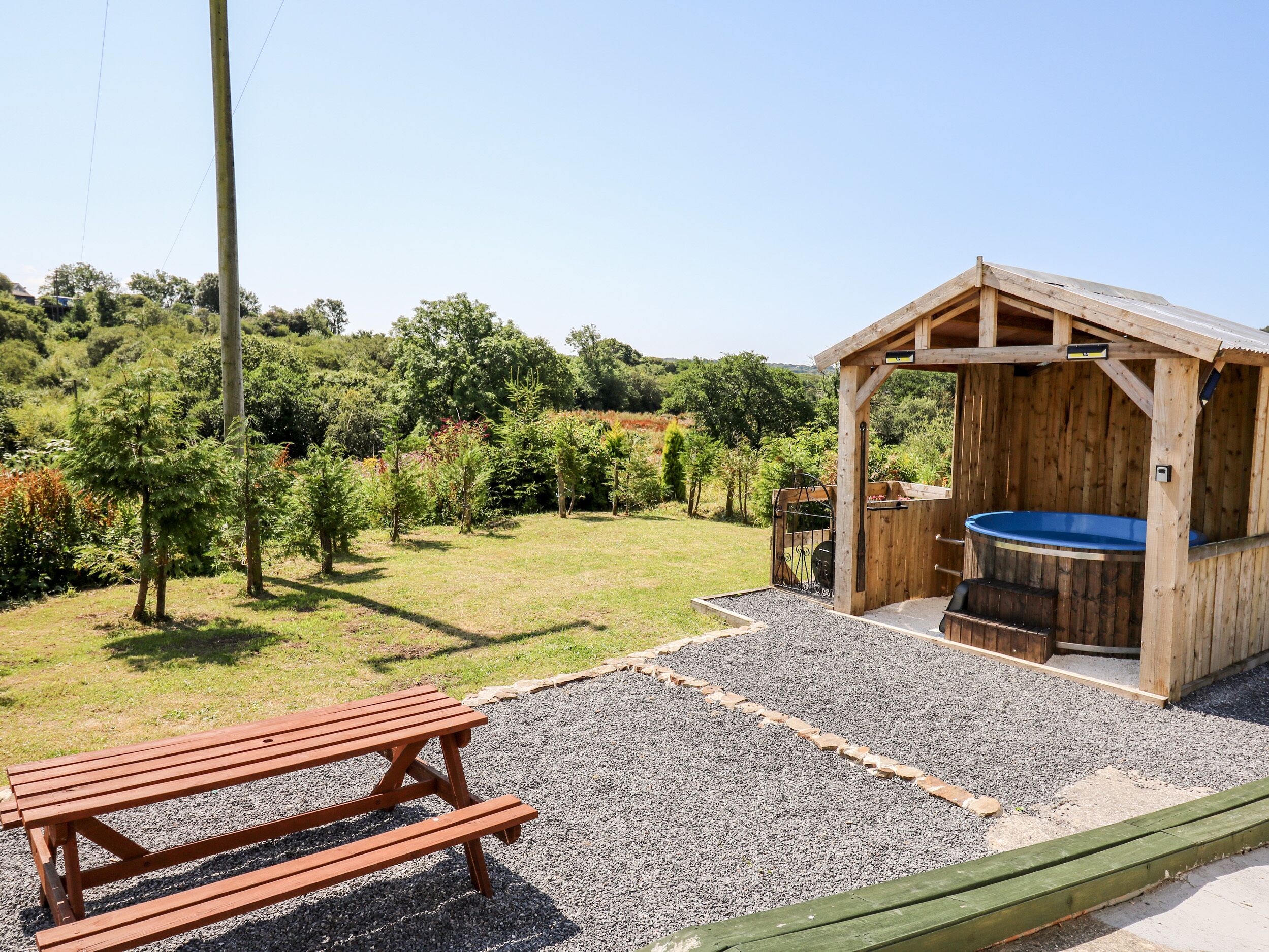 Ein Sitzbereich im Freien mit Holzboden, einem Picknicktisch und einem Whirlpool.