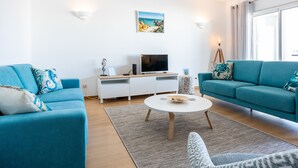 A modern living room with two teal sofas, a white entertainment unit, a flat-screen TV, and a framed picture on the wall. - Lagos Workation Apartment (Lagos)