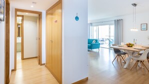 A modern hotel room with a wooden wardrobe, a dining area with a table and chairs, and a bright living space with a blue sofa. - Lagos Workation Apartment (Lagos)