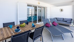 A modern outdoor dining area with a wooden table, blue and red cushions, and a view of the adjacent living area. - Lagos Workation Apartment (Lagos)