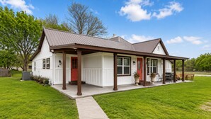 A single-story house with a front porch, a red door, and a covered patio area.
