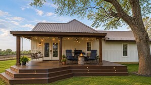 A covered outdoor patio with a grill, seating, and a fire pit.