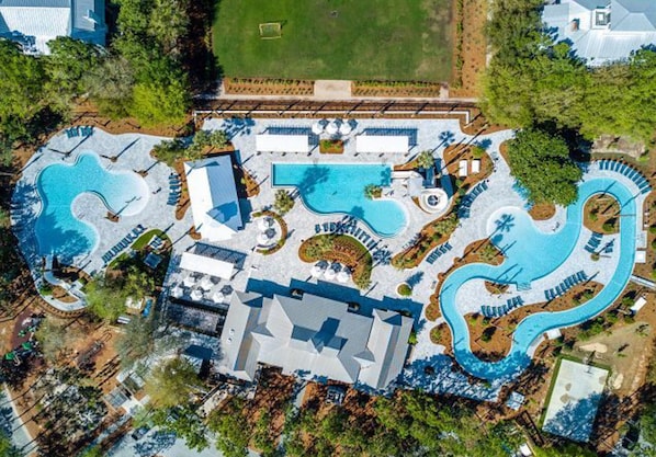 Vista aérea de un resort con múltiples piscinas, un edificio grande y vegetación circundante.