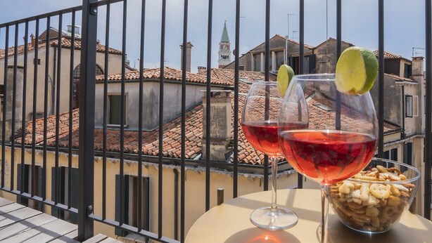 A balcony with two wine glasses, one with a lime slice, and a bowl of snacks. - Corte Rubbi 11 Secret Terrace Apartment (Venice)