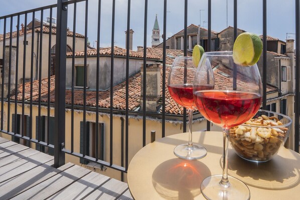 A balcony with two wine glasses, one with a lime slice, and a bowl of snacks.