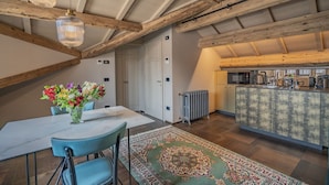 A dining area with a table, chairs, a vase of flowers, and a patterned rug. - Corte Rubbi 11 Secret Terrace Apartment (Venice)