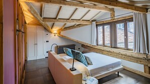 A bedroom with a sloped ceiling, a bed, a radiator, a window with curtains, and a door. - Corte Rubbi 11 Secret Terrace Apartment (Venice)