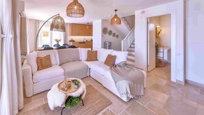 Ein modernes Wohnzimmer mit einem Ecksofa, einem runden Couchtisch und einer Treppe, die zu einer weiteren Ebene führt.