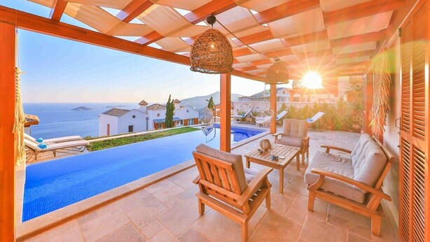 Ein überdachter Außenbereich mit Pool, Holzmöbeln und Blick aufs Meer.