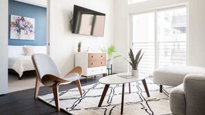 Una sala de estar moderna con un sof á, un sillón, una mesa de centro y un televisor de pantalla plana montado en la pared.